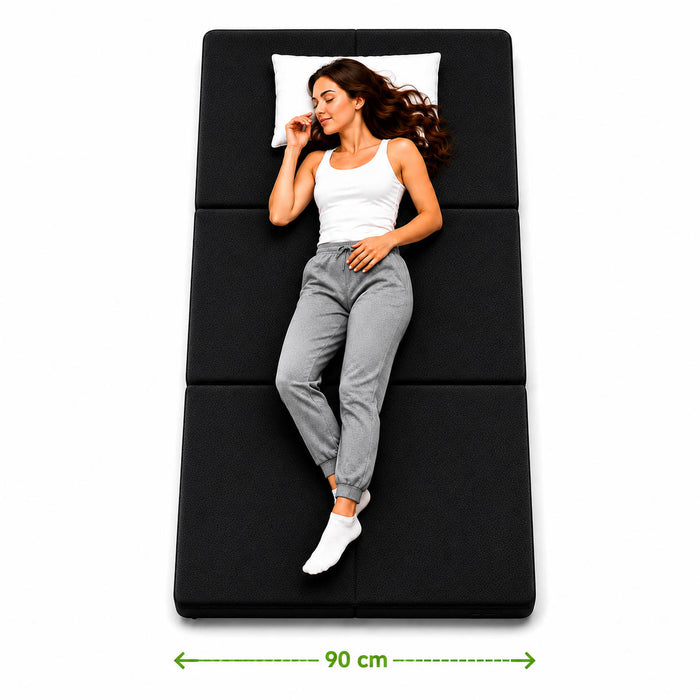 Faltmatratze 90x200 in Anthrazit aufgeklappt, eine Person zeigt die 90 cm Liegebreite #typ=groessenfoto;farbe=anthrazit;groesse=90x200;pos=2